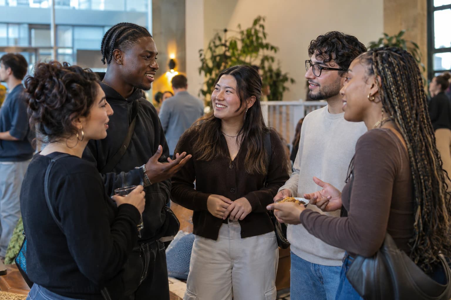 Five young adults from varied backgrounds talking at a community gathering.